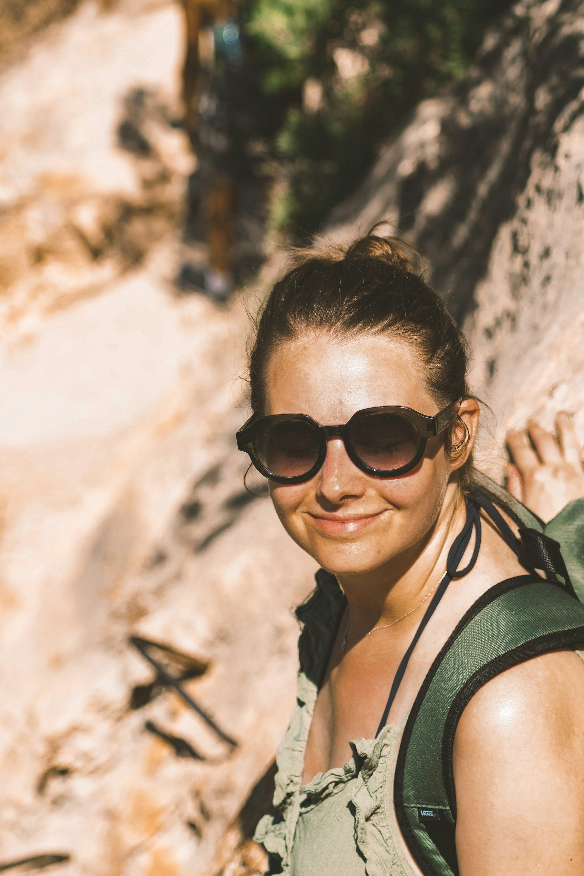 A hiker smiling in the sun against a sandstone canyon wall