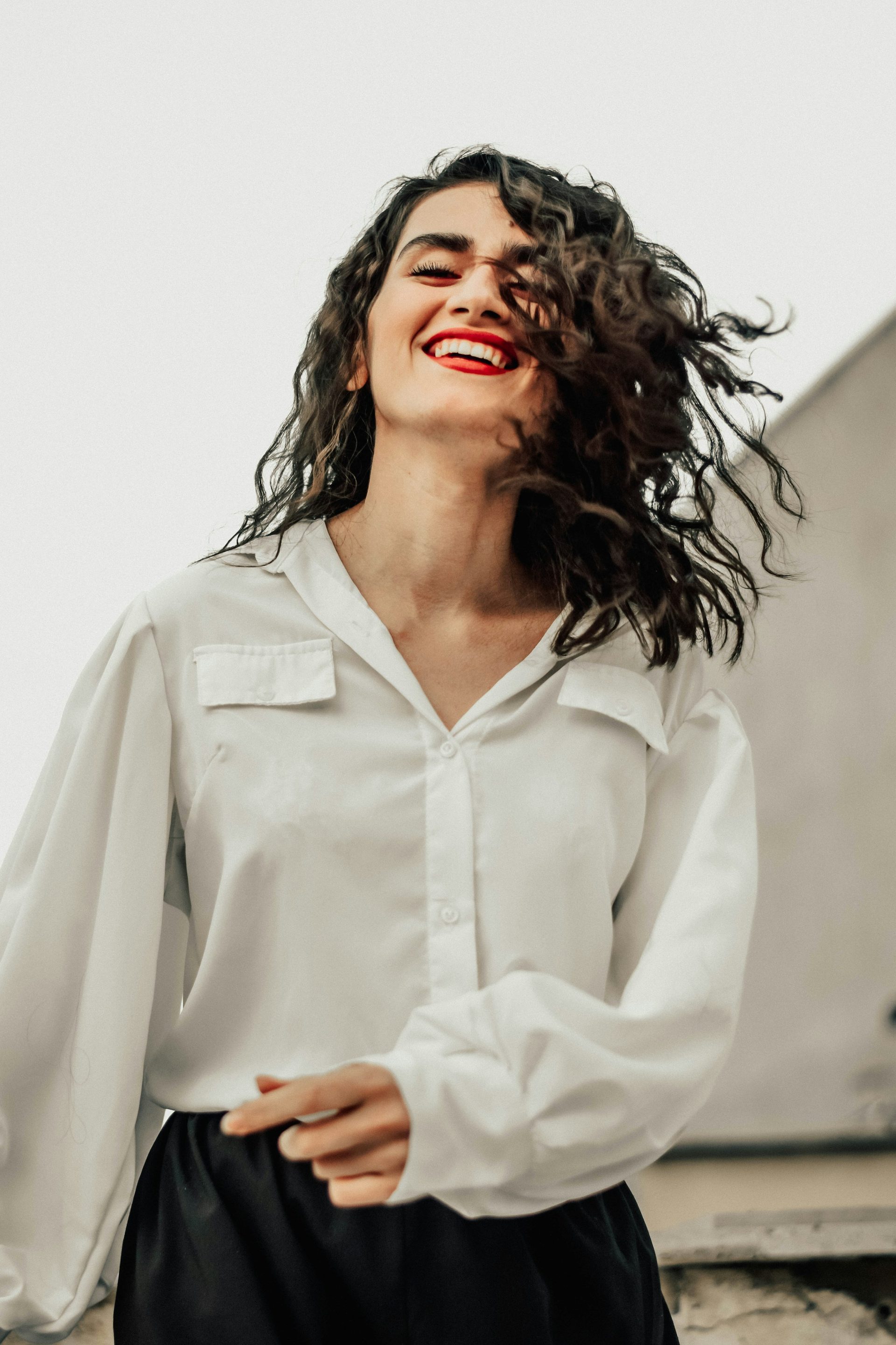 A woman laughing, her dark curls caught in the breeze